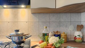 Une cuisine équipée d’une cuisinière, de casseroles, d’une planche à découper avec des légumes et d’ustensiles de cuisine.