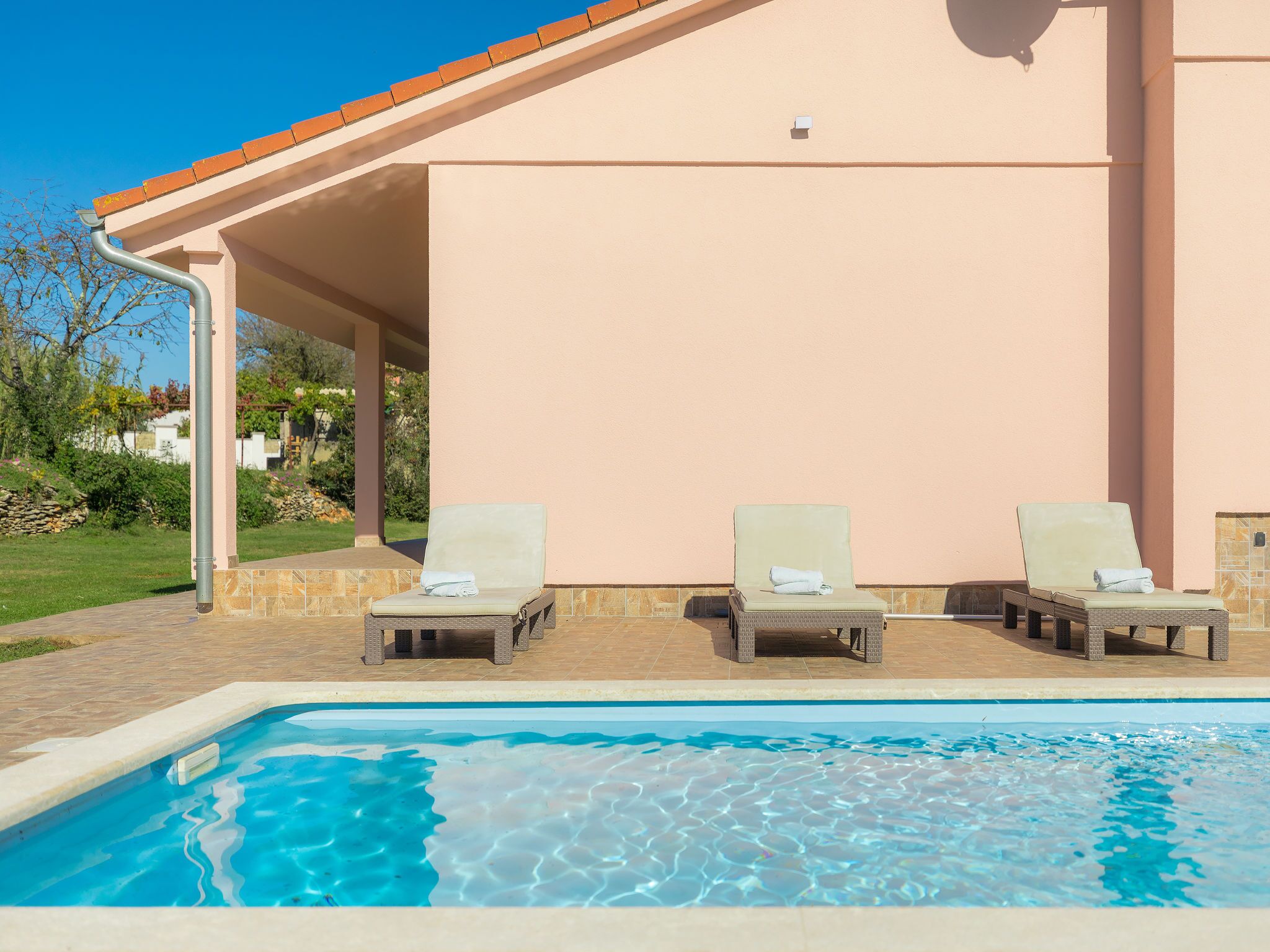 A poolside area with two lounge chairs and a swimming pool.