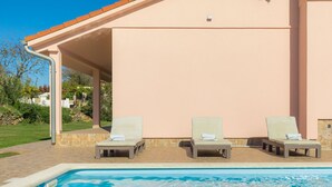 Un espace aménagé au bord de la piscine, comprenant deux chaises longues et une piscine.