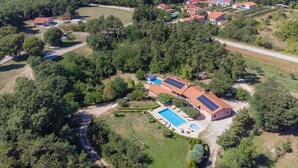 An aerial view of a residential area with multiple houses, a swimming pool, and solar panels on the roofs.