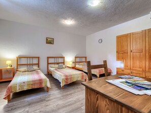 A room with two wooden beds, a wooden desk, and a large wardrobe.