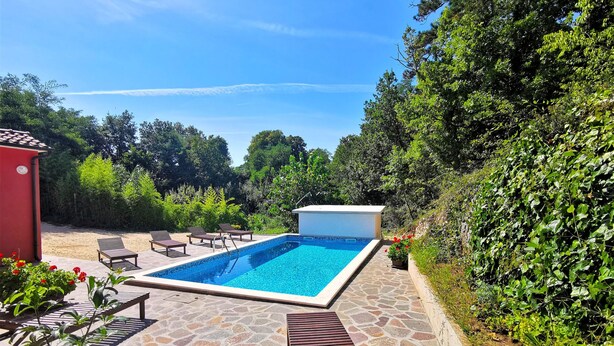A swimming pool with lounge chairs and a stone patio.