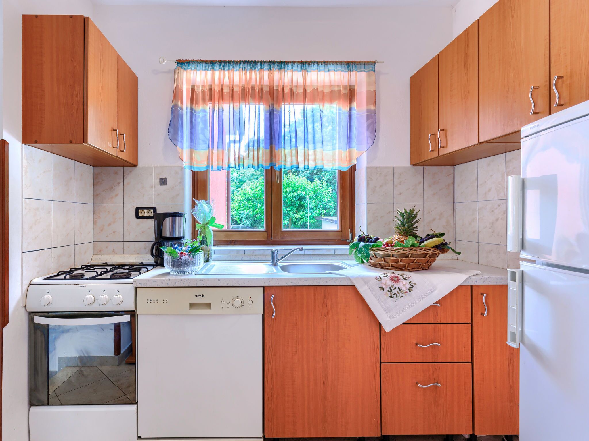 Una cocina con armarios de madera, estufa a gas, lavavajillas y refrigerador.