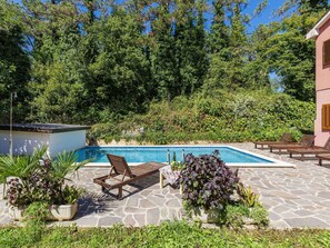 A swimming pool with lounge chairs and potted plants.