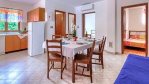 A compact kitchen with wooden cabinets, a white refrigerator, and a dining area with a table set for four.