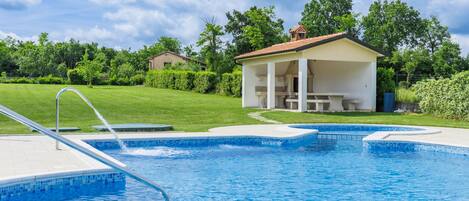 Una piscina amb una zona de seients coberta i un petit pavelló.