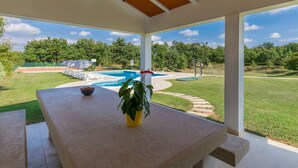 A covered patio with a pool, outdoor seating, and a view of the surrounding landscape. - Apartment Macini by Interhome (Rovinj)
