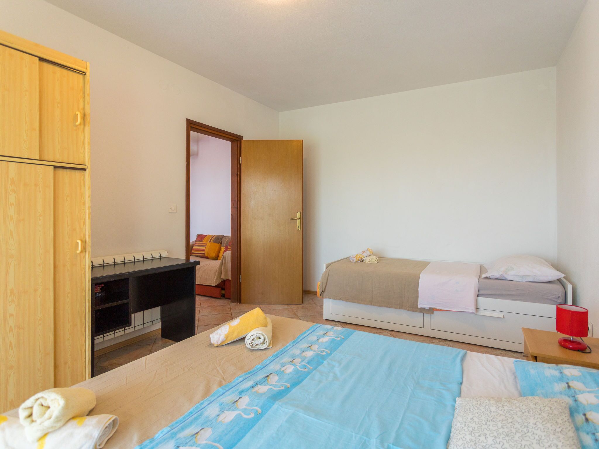A bedroom with a bed, a desk, and a wardrobe.