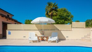 A swimming pool with two white lounge chairs and a table under a white umbrella. - Vacation home Medica by Interhome (Pazin)