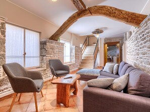 A cozy living room with stone walls, a wooden staircase, and a modern sofa. - Vacation home Narcis by Interhome (Pazin)