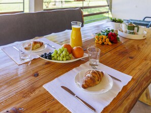 Enjoy a casual breakfast with a selection of fresh fruits, a warm croissant, and a steaming coffee.