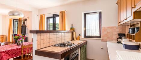 A kitchen with a gas stove, oven, and a dining area with a table and chairs.