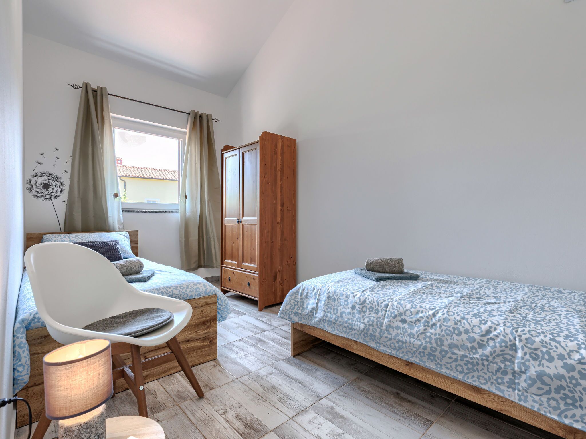 A bedroom with a bed, a chair, a wardrobe, and a window.