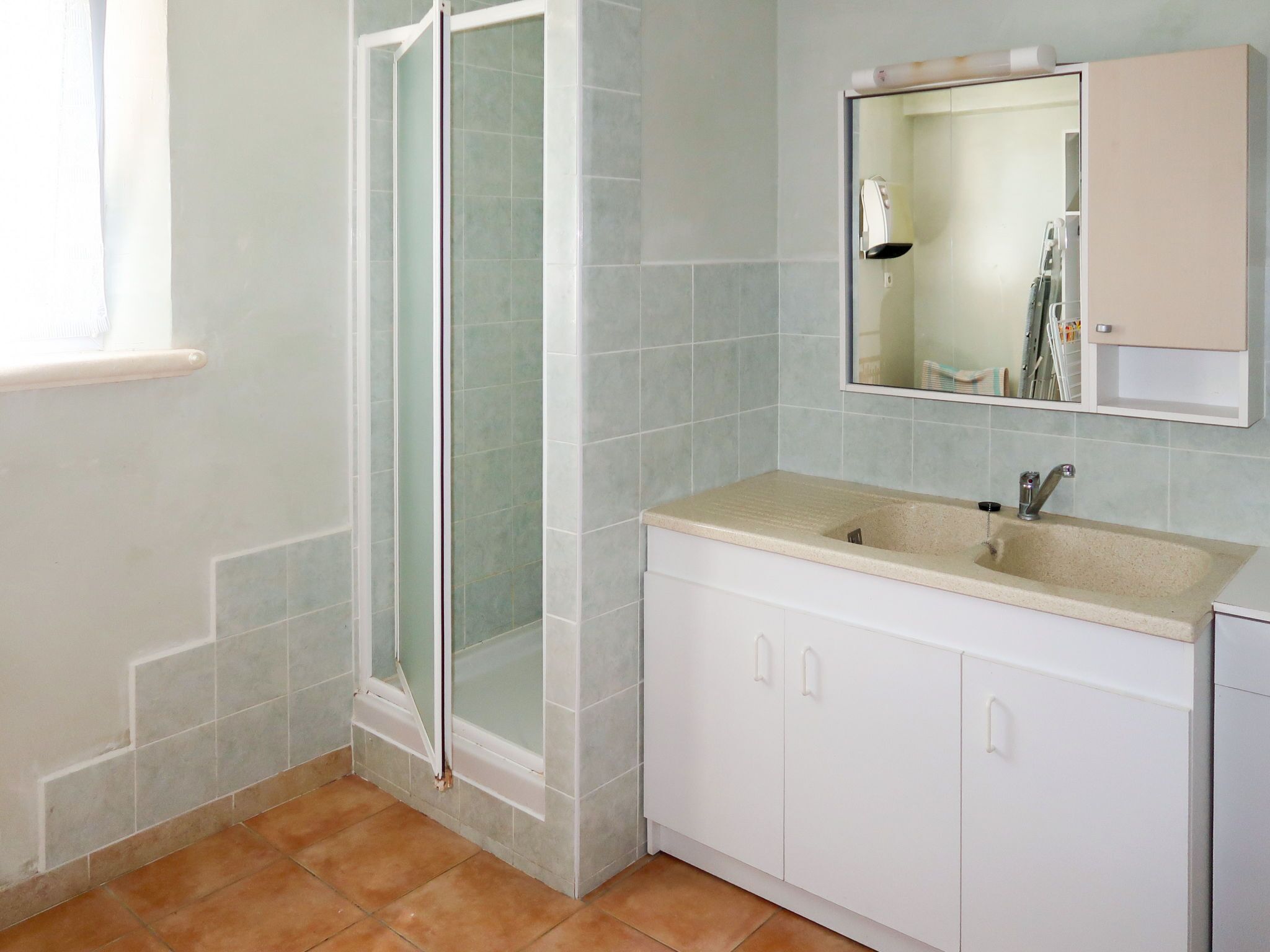 Een badkamer met een douche, wastafel en kastjes.