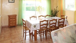 A dining area with a table and chairs, a sofa, a small cabinet, and a window with curtains. - Plan du Vas by Interhome (Valreas)