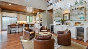 A spacious kitchen with white cabinets, a stainless steel refrigerator, and a bar area with stools. - Featured on Staycation: The Overlook | Pool, Pickleball, ATV Access & Views (Broken Bow)