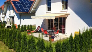 Uma casa com varanda, painéis solares e um jardim.