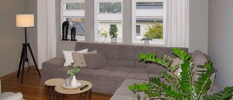 A living room with a sofa, a coffee table, a lamp, and a potted plant.