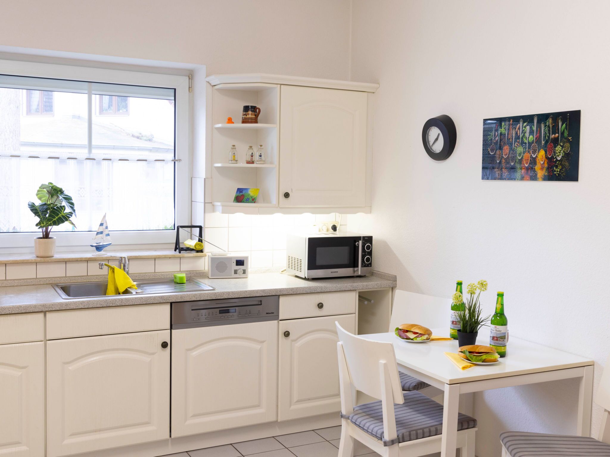 A compact kitchen with white cabinetry, a microwave, a sink, and a small dining area with a table and chairs.
