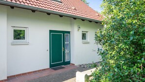 Un bâtiment blanc avec une porte verte, une petite fenêtre et le numéro « 21b » sur le mur.