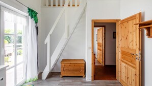 A staircase with white railings, a wooden bench, and a wooden door leading to another room.