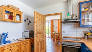 A kitchen with wooden cabinets, a microwave, an oven, and a dining area with chairs and a table.
