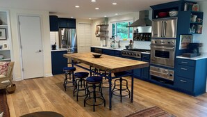 Una cocina moderna con una isla central, taburetes de bar y electrodomésticos de acero inoxidable.