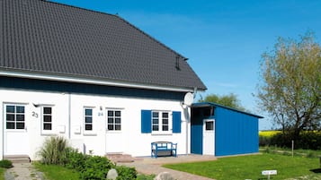 Ein weißes Gebäude mit blauen Fensterläden, mit den Hausnummern 23 und 24, und ein kleiner blauer Schuppen.