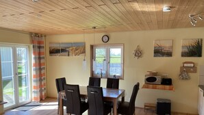 Un comedor con una mesa y sillas de madera, un reloj en la pared y un ventanal con vistas al exterior.