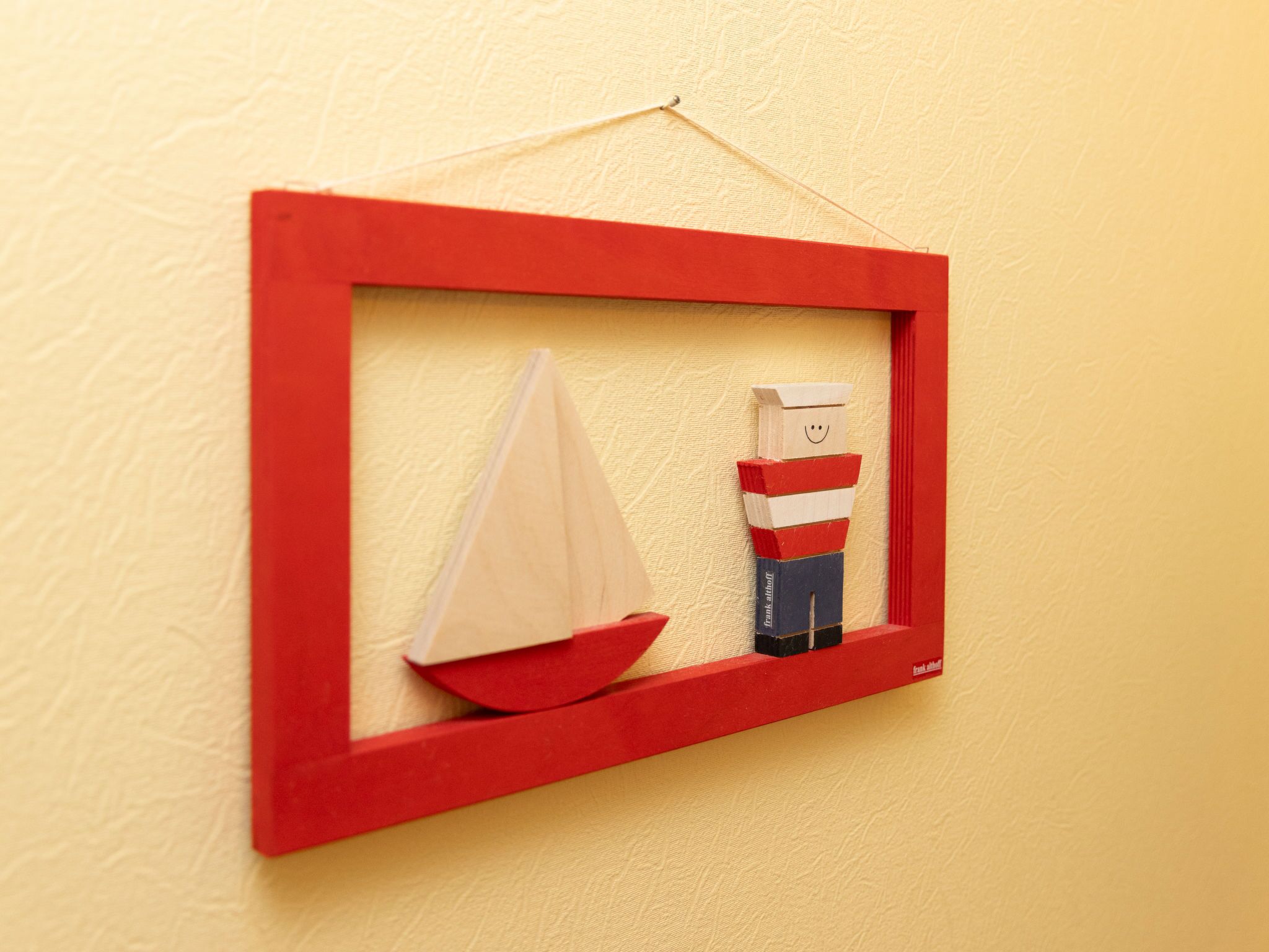 A framed artwork of a sailboat and a figure on a wall.