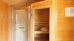 A wooden sauna room with a glass door, a bench, and a towel rack.
