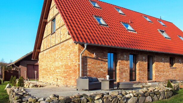 A brick building with a red-tiled roof, stone walls, and a stone pathway leading to outdoor seating. - zum Katzengrund II by Interhome (Woldegk)