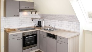 A compact kitchen with grey cabinets, a built-in oven, a dishwasher, and a window above the sink. - zum Katzengrund II by Interhome (Woldegk)