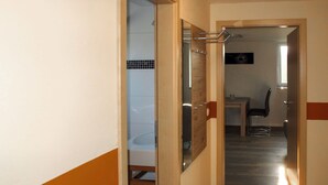 A hallway with a wooden floor, a door leading to a bathroom with a tiled wall, and a chair in the background. - zum Katzengrund II by Interhome (Woldegk)