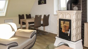 A modern living room with a sofa, a dining table with chairs, and a wood-burning stove. - zum Katzengrund II by Interhome (Woldegk)