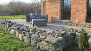 A brick house with a red roof, a stone wall, and a patio with outdoor furniture. - zum Katzengrund II by Interhome (Woldegk)