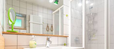 A modern bathroom with a white sink, mirror, and shower.