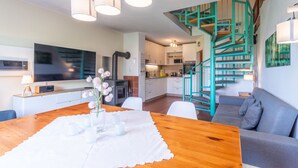 A modern kitchen with a built-in oven and microwave, a dining area with a wooden table and chairs, and a teal spiral staircase leading to an upper level. - Schlossberg by Interhome (Zandt)