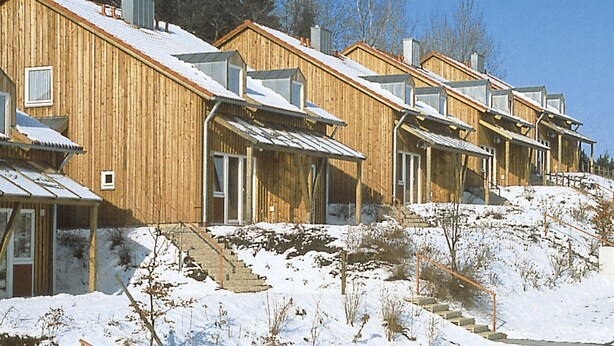 A row of wooden cabins with sloped roofs, each featuring a small porch and a window. - Schlossberg by Interhome (Zandt)