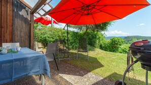 An outdoor patio with a table, chairs, a grill, and a red umbrella. - Schlossberg by Interhome (Zandt)