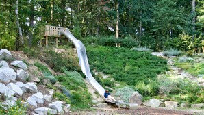 A playground with a slide, surrounded by rocks and greenery. - Ferienhäuser Schlossberg by Interhome (Zandt)
