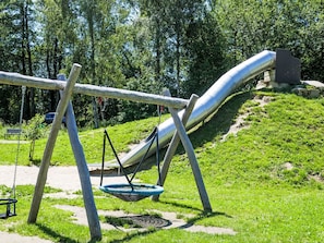 A playground with a slide, swings, and a hanging basket.
