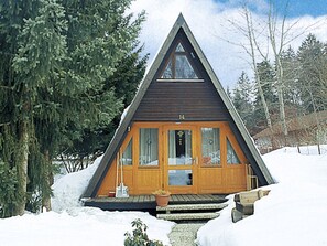 A wooden cabin with a triangular roof, a front porch with steps, and a door with glass panels. - Jägerwiesen ND 5 by Interhome (Waldkirchen)