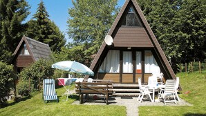 A triangular-roofed cabin with a patio area, outdoor seating, and a satellite dish. - Jägerwiesen ND 4 by Interhome (Waldkirchen)