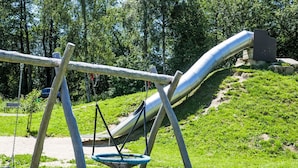 A playground with a slide, swings, and a hanging basket. - Jägerwiesen ND 4 by Interhome (Waldkirchen)