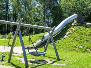 A playground with a slide, swings, and a hanging basket. - Jägerwiesen ND 4 by Interhome (Waldkirchen)