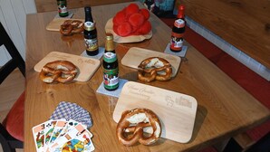 Ein Holztisch mit Brezeln, Bierflaschen und Spielkarten.