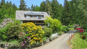 Ein Chalet mit Steinaußenseite, Solaranlage und einem Garten mit verschiedenen Blumen.