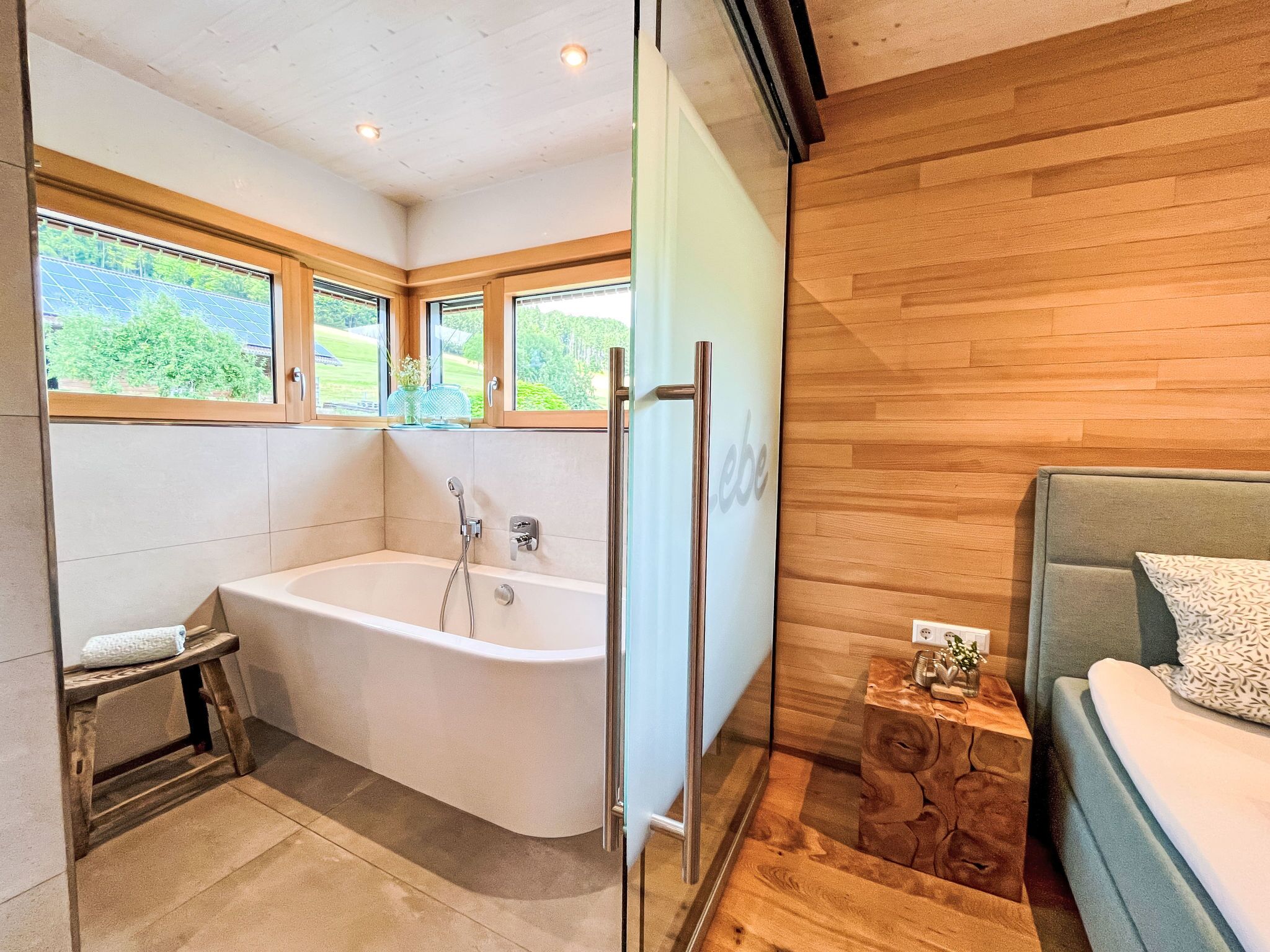 A modern bathroom with a freestanding bathtub, a glass shower enclosure, and a wooden vanity with a sink.