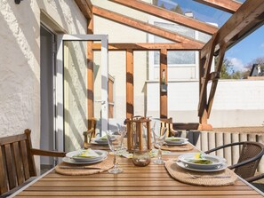 An outdoor dining area with a wooden table set for four, surrounded by wicker chairs. - Vacation home Bruni by Interhome (Manderscheid)